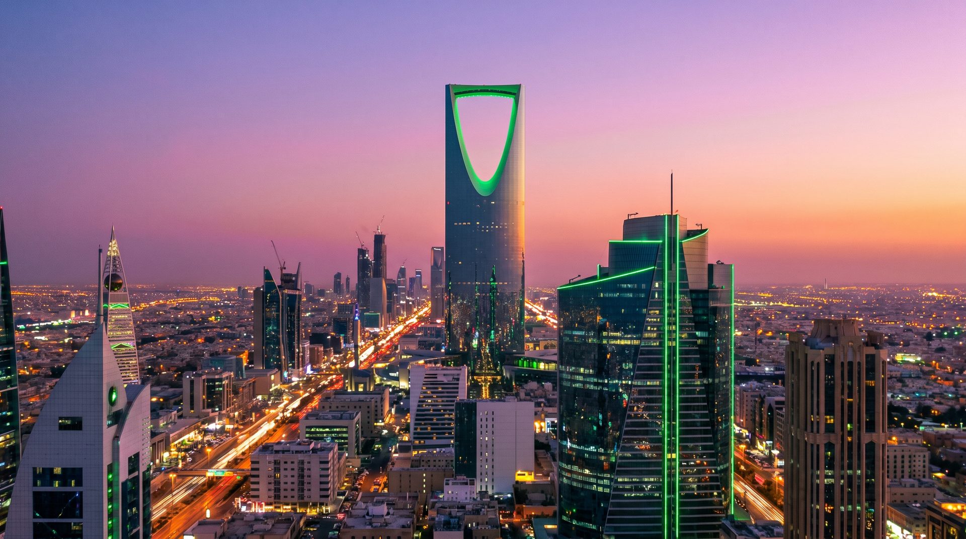 Riyadh financial district skyline at twilight with green LED accent lighting.
